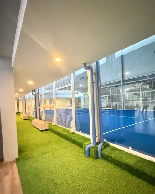Turf walkway alongside the glass padel courts