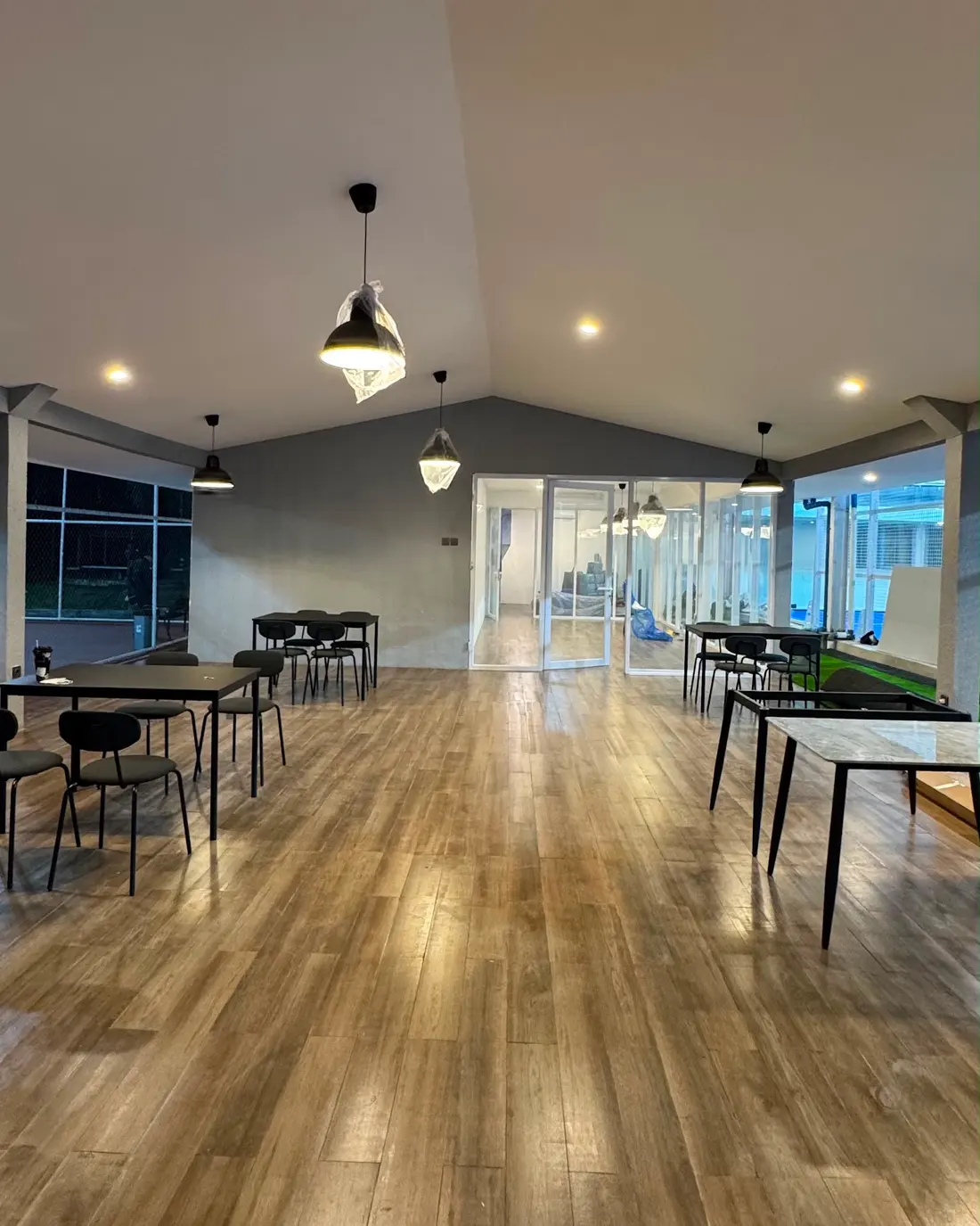 Bright seating hall with wood floors and pendant lights